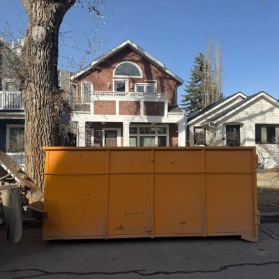 Equi-Waste Services Ltd large orange dumpster bin rental placed on residential street in sunny neighborhood